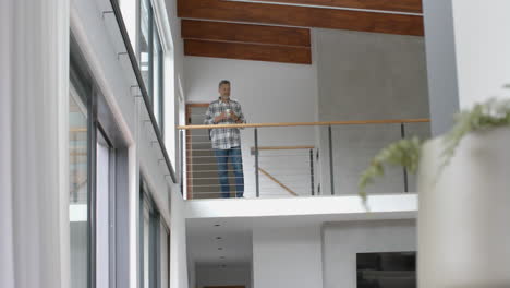 hombre de dos razas senior mirando a la ventana, bebiendo café en el piso de arriba, aterrizaje, espacio de copia, cámara lenta