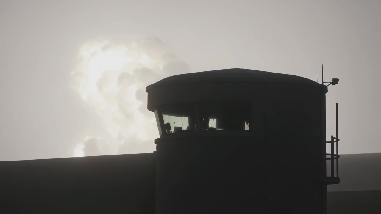 Torre di guardia con due guardie alle finestre del sito, un bagliore emerge dall'orizzonte sinistro, indicando attività
