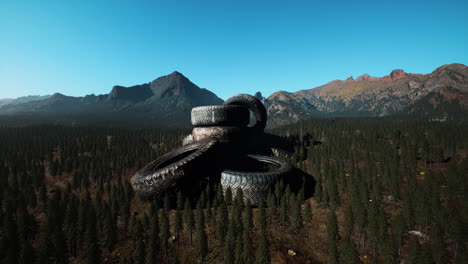 concept of environmental pollution with big old tires in mountain forest