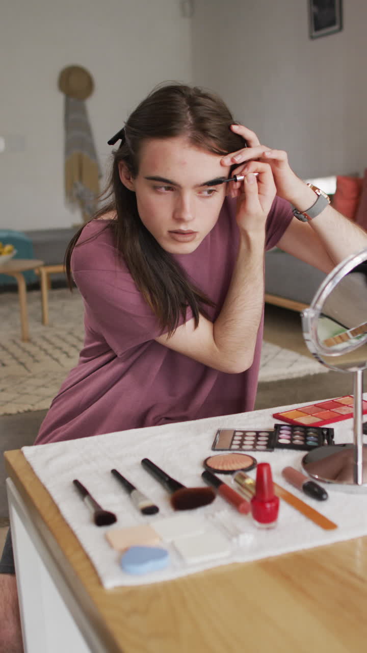video vertical de una mujer transgénero caucásica no binaria haciendo maquillaje