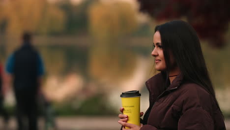 Retrato-De-Una-Mujer-Joven-Y-Bonita-Caminando-Por-El-Parque-Con-Un-Café-En-Iulius,-Cluj-napoca,-Rumania