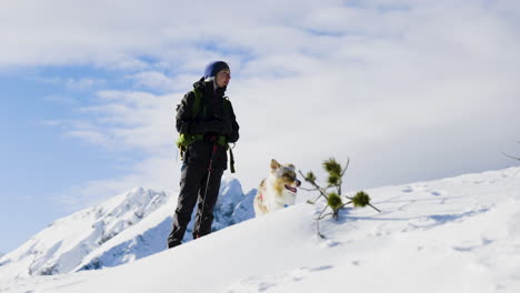 woman and dog hiking in snowy mountains