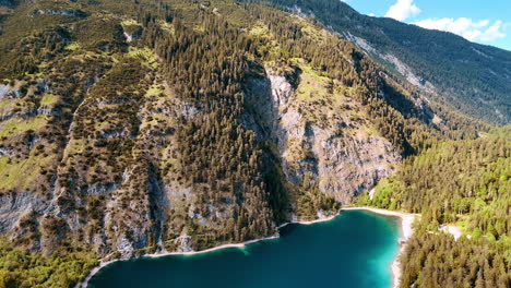 flying above the turquoise lake in the mountains. view on the unapproachable rocks overgrown with evergreen woods.
