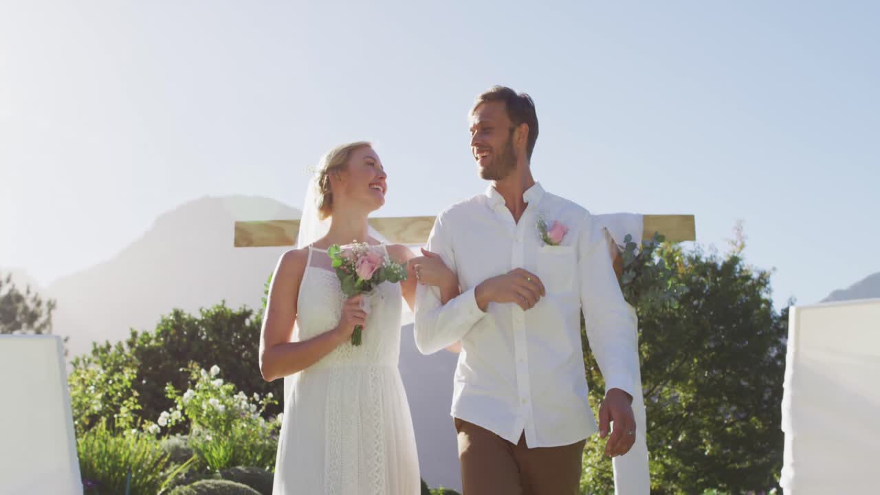 retrato de una feliz pareja de recién casados caucásicos, caminando por el altar al aire libre