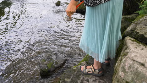 a lady pull up the rope to check her find and drop the neodymium magnet into the water again for more catches, trendy hobby magnetic fishing