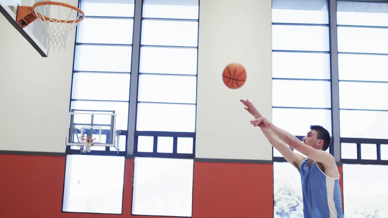 jugador de baloncesto masculino caucásico disparando pelota en el aro, entrenamiento en la cancha cubierta, cámara lenta