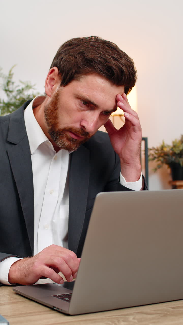 Middleaged businessman opens pay cut email on laptop sighs at bad news frowns with worry very sad