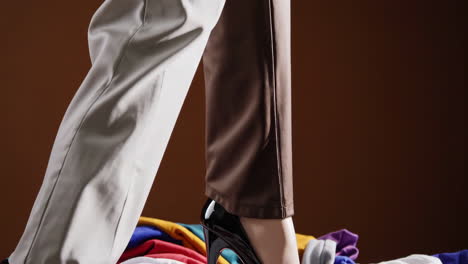 legs in pants with high heel standing on colorful clothes