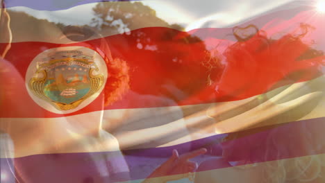 animation of waving costa rica flag over group of friend on the beach