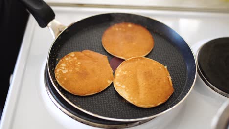 close-up of three golden ruddy pancakes in a frying pan, light white steam.