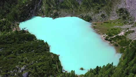 lake sorapis bright turqoise water in the dolomites italy, rising tilt down aerial