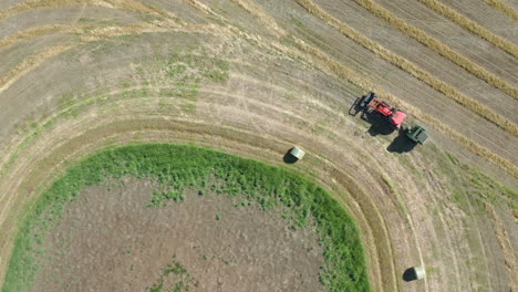 tractor empacando heno en el amplio campo en saskatchewan, canadá - toma aérea