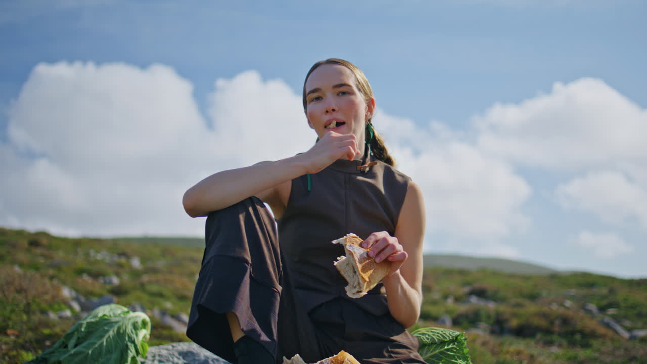 푸른 구름이 가득한 하늘에서  조각을 먹는 야외 소녀. 조용한 여행자 식사를 즐기십시오.