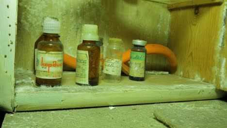 old medical bottles, accessories inside the abandoned soviet underground bomb shelter, old soviet cold war bunker, apocalypse, close up handheld shot