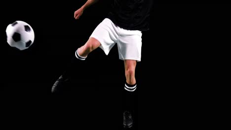 athlete practicing soccer against black background