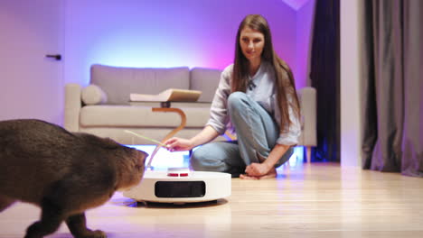 mujer interactuando con su gato y un aspirador robot