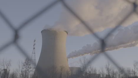 smoke stack from behind fence in slo-mo