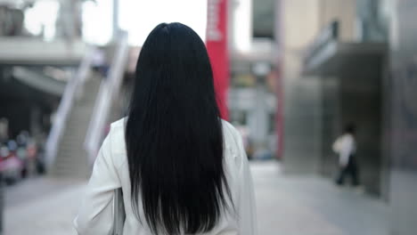 woman with long black hair walking in an urban environment