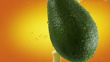 aguacate con rebanadas y salpicaduras cayendo sobre un fondo naranja