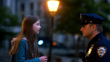 police officer and child talking on city street at night