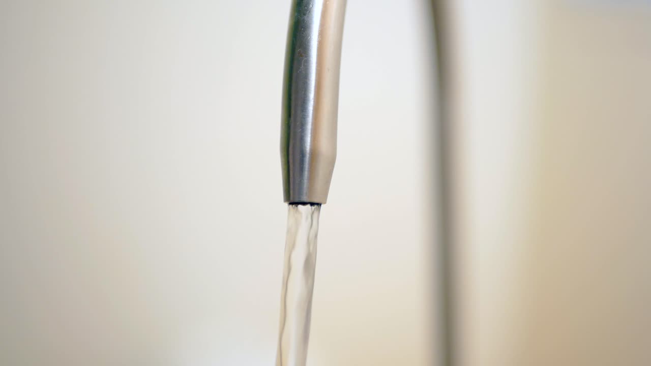 Vand der hældes fra en vandhane i slowmotion