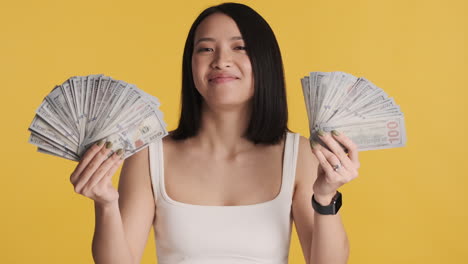 Asian-woman-looking-happy-while-holding-money-on-camera.