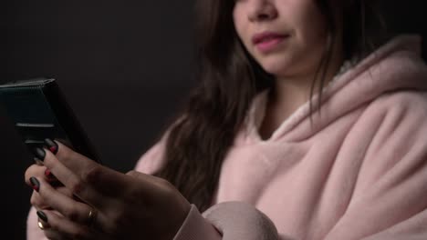 a woman interacts with her smartphone in a dimly lit environment, with the screen light subtly illuminating her face. set against a dark background