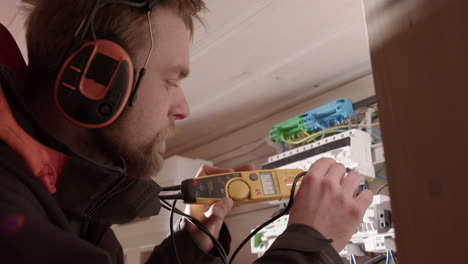 Licensed electrician use voltmeter to test current at residential electric panel