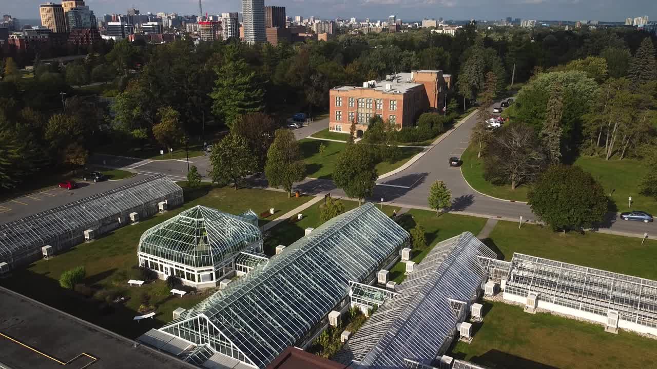 Ottawa city skyline beyond large glass greenhouse at experimental farm