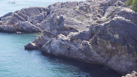 Una-Persona-Escalando-El-Acantilado-Desde-El-Agua