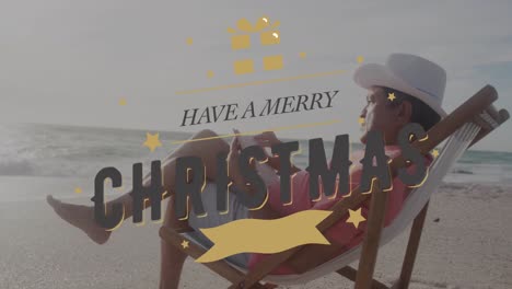 Animación-De-Tener-Una-Feliz-Navidad-Sobre-Un-Hombre-Hispano-Mayor-Tomando-El-Sol-Con-Un-Libro-En-La-Playa