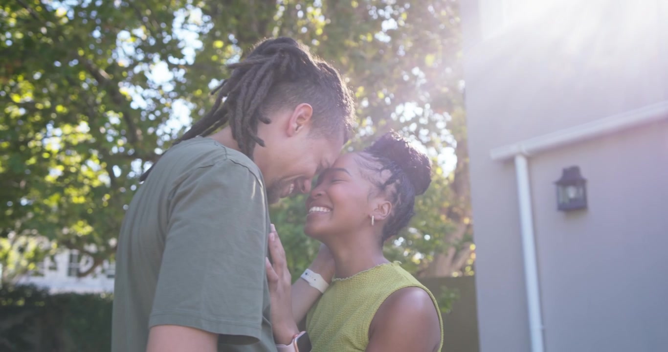 African American couple man cupping face starting forehead touch showing love under tree by house