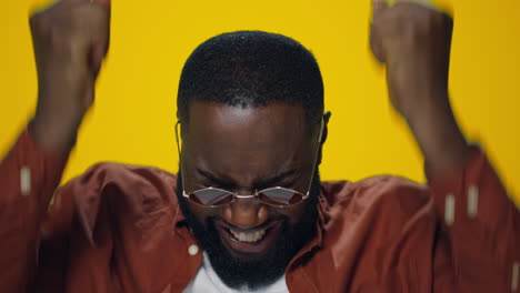 Closeup-excited-african-american-guy-showing-yes-gesture-on-yellow-background.