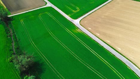 aerial-shot-of-plowed-farmland-and-green-fields,-4k