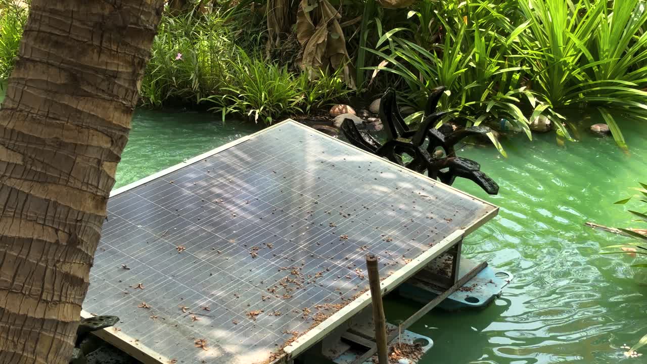 Close-up of a solar cell paddle wheel aerator running in a small canal of a farm. Space for text and landscape footage of a Solar cell paddle wheel aerator in a small canal. Real-time footage.