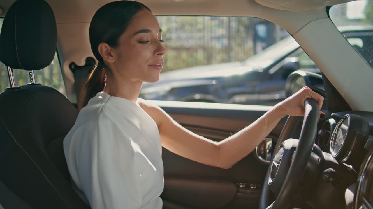 자신감 있는 여성 운전자 가 값비싼 자동차 에 앉아 스마트폰 메시지 를 가까이 보고 있다