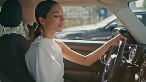 mujer confiada conductor sentado en un coche caro buscando mensaje de teléfono inteligente de cerca