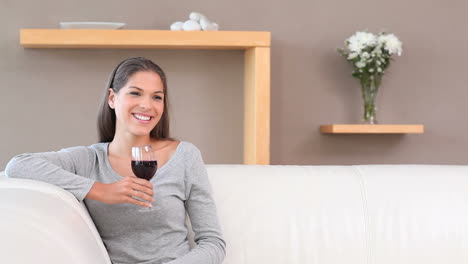una mujer morena bebiendo vino rojo.