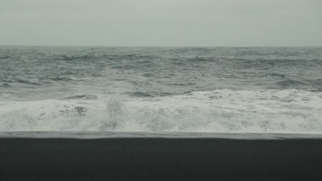 waves crash on a black sand beach in iceland