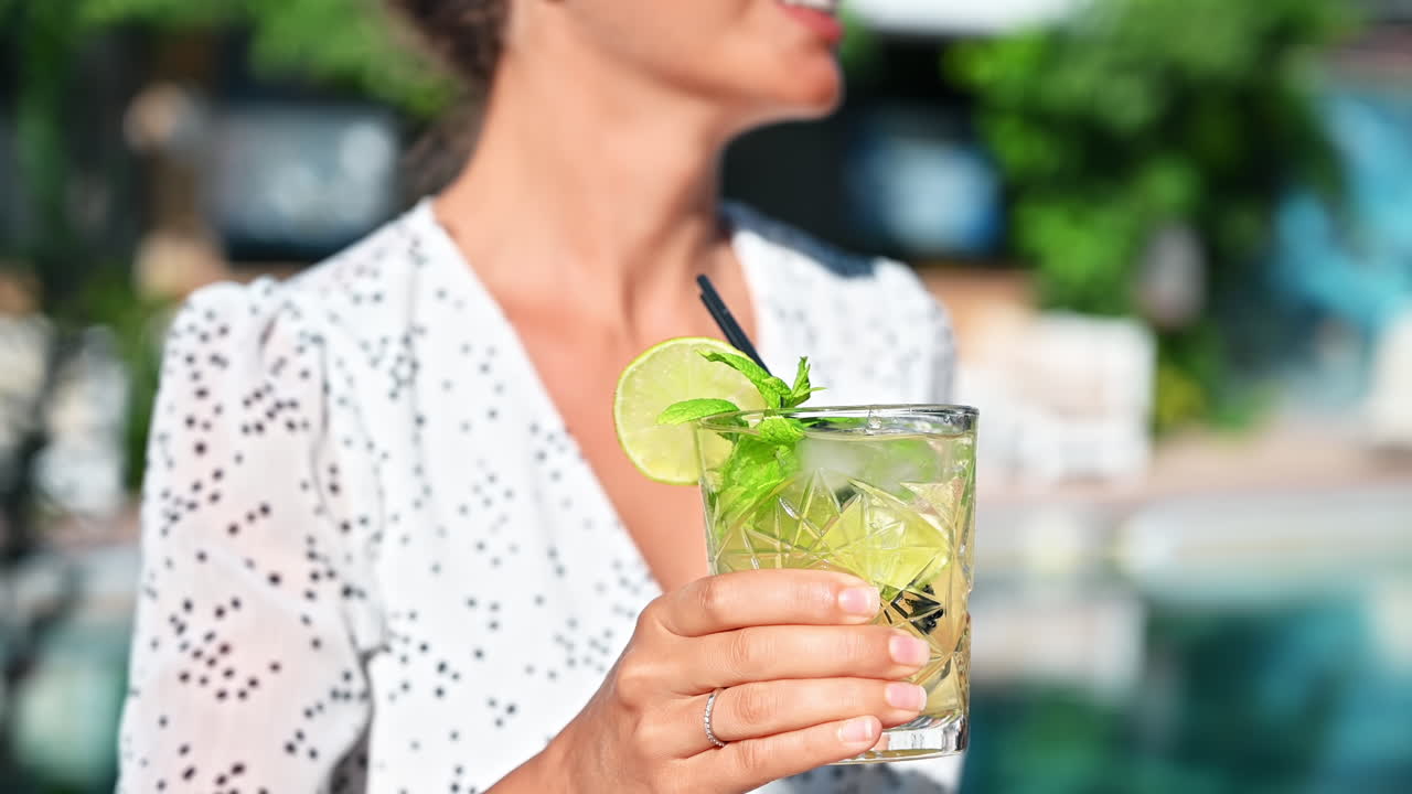 Woman holding a cocktail with ice, slice of lime in Greece