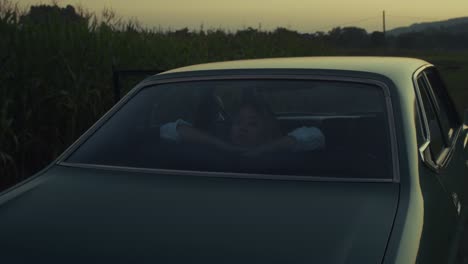 woman in a vintage car at sunset