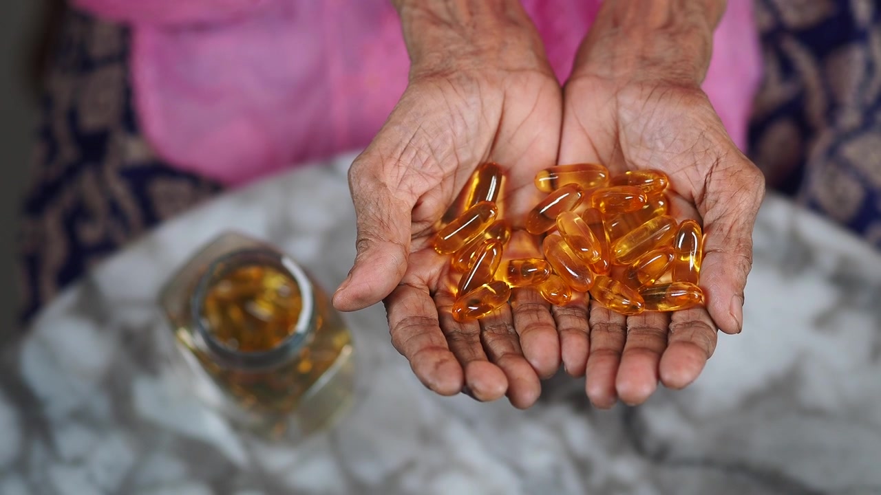 Persona anziana che tiene in mano capsule di olio di pesce Omega-3.