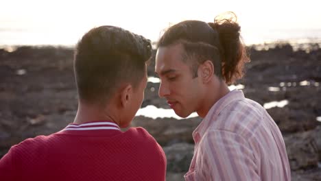 happy diverse gay male couple embracing at beach, slow motion