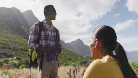 african american couple talking to each other while trekking in the mountains