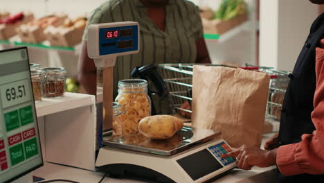 comerciante que utiliza la balanza en la caja registradora en una tienda orgánica