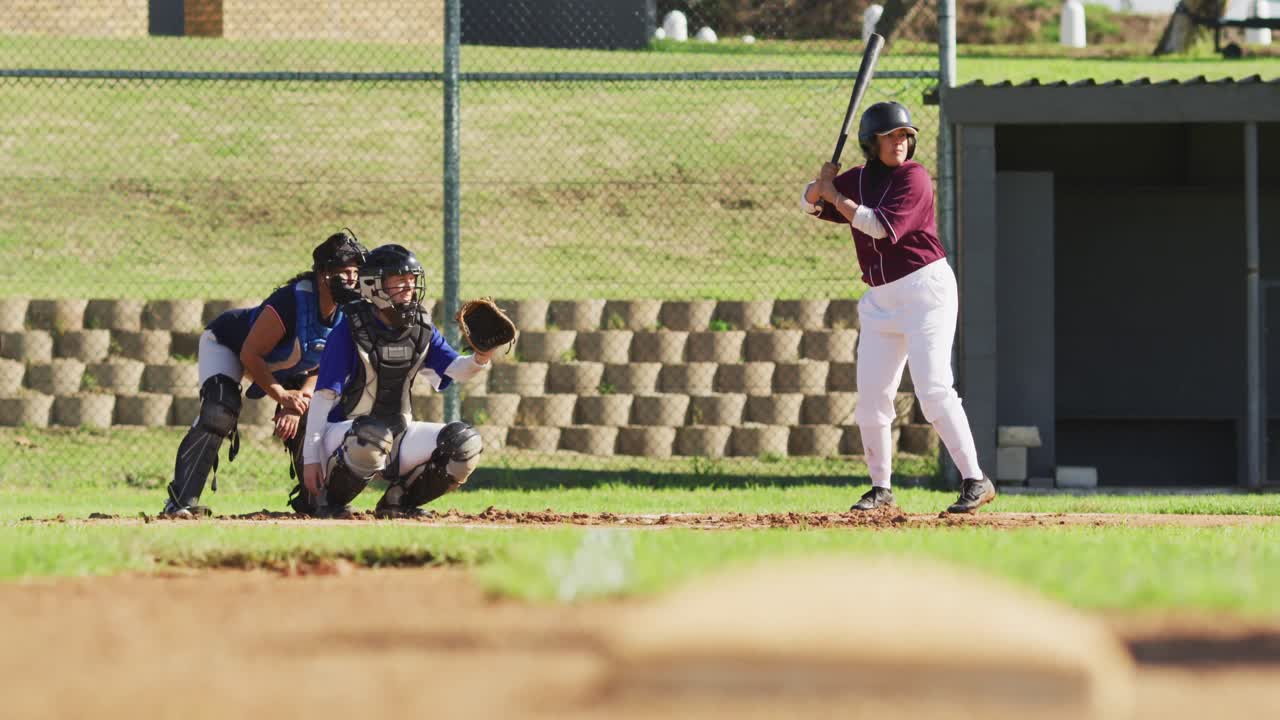 Gruppo eterogeneo di giocatrici di baseball che giocano sul campo, battitrice che si prepara a colpire la palla lanciata.