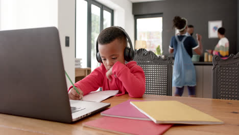african american boy in online class using headphones and laptop, slow motion