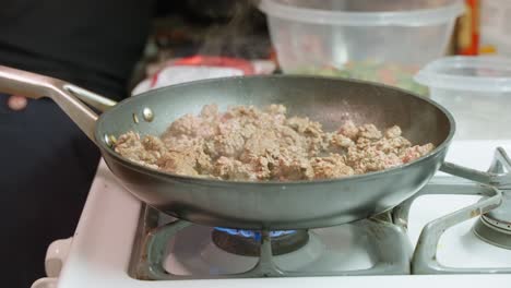 Browning-beef-mince-sizzling-in-frypan-on-domestic-gas-stove-close-up