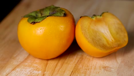 two persimmons displayed on a wooden surface