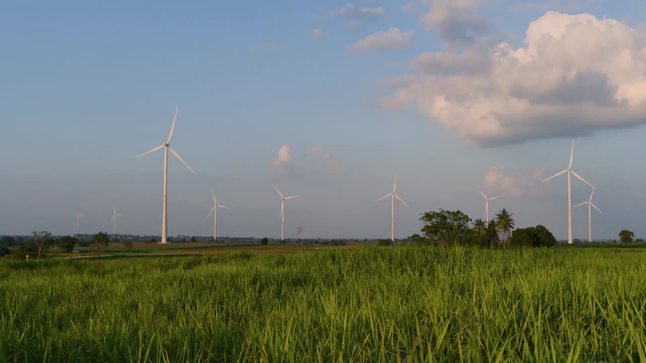 태국과 동남아시아 본토의 먼지 구름, 깨끗한 대체 에너지를 만들어 트럭이 지나갈 때 해가 지는 동안 농지에서 풍력 터빈이 발사됩니다.